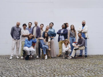 Eine Gruppe Menschen posiert vor einer weißen Wand, es ist das hannoversche Orchester im Treppenhaus.