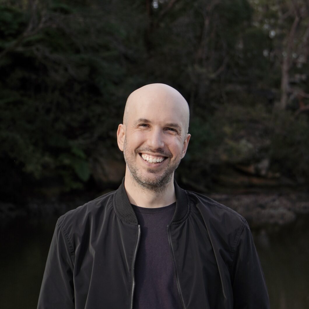 Portrait eines jungen, weißen Mannes mit Glatze in schwarzem Hemd, es ist Komponist Charlie Sdraulig.
