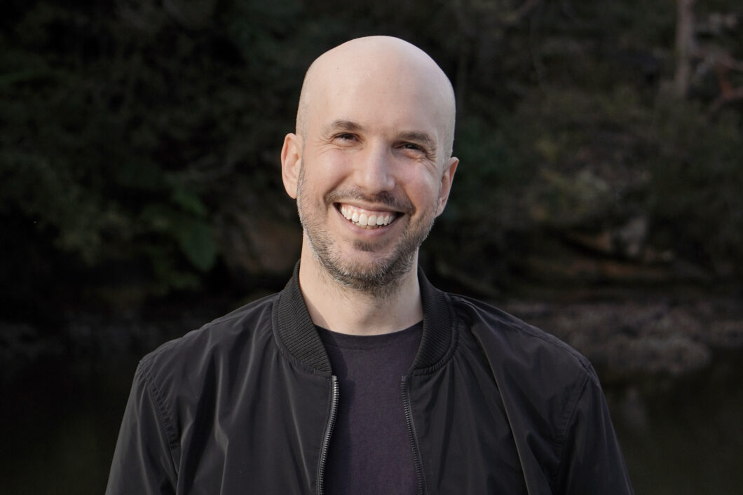 Portrait eines jungen, weißen Mannes mit Glatze in schwarzem Hemd, es ist Komponist Charlie Sdraulig.