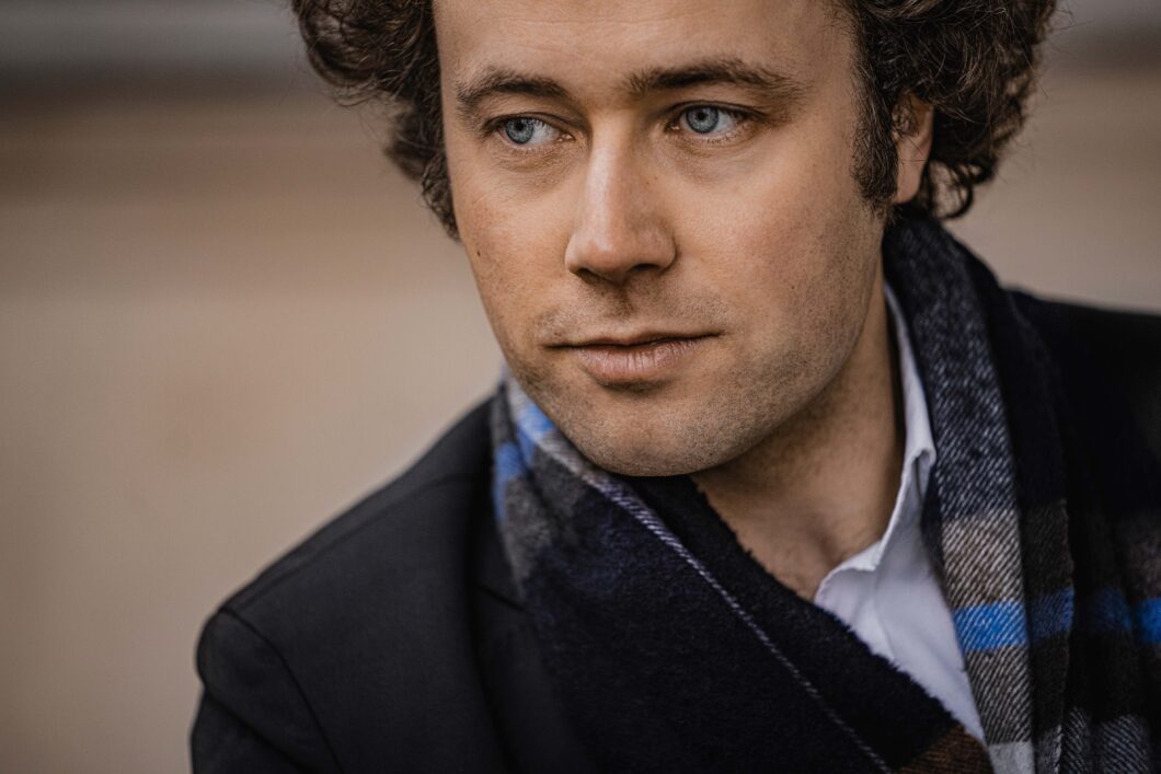 Ein Mann mit kurzen dunklen Haaren schaut verträumt in die Ferne, es ist Pianist Alexander Schimpf.