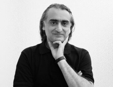 Schwarz-weiß-Foto: Ein Mann mit zurückgelegten halblangen Haaren schaut in die Kamera und hält nachdenklich die linke Hand ans Kinn. Es ist der Komponist Ehsan Khatibi.