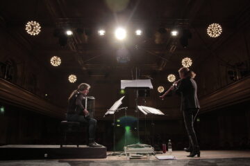 Zwei Frauen spielen auf einer Bühne Akkordeon und Schalmei, Scheinwerfer und Lichter.