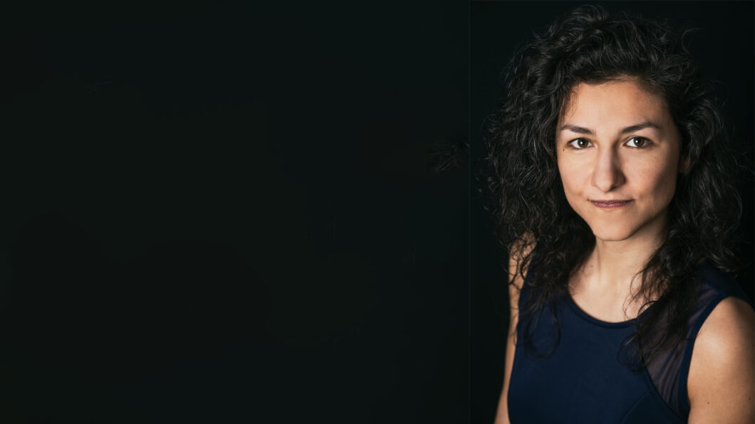 Portrait einer jungen Frau mit dunklen Locken vor schwarzem Hintergrund. Es ist Marijana Janevska