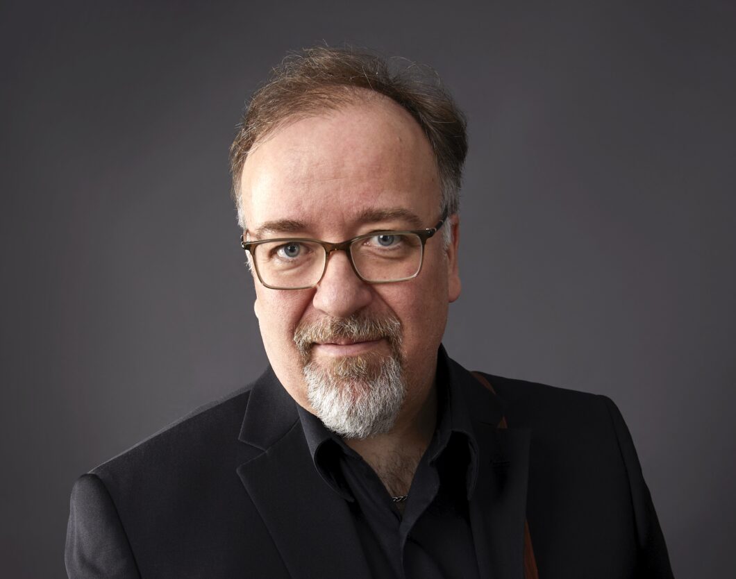 Ein Mann mit Brille und grauem Bart, es ist der Komponist Paul Frehner.